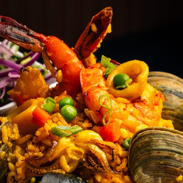 Close-up of Peruvian arroz con mariscos, featuring shrimp, clams, squid, and vegetables over yellow rice.