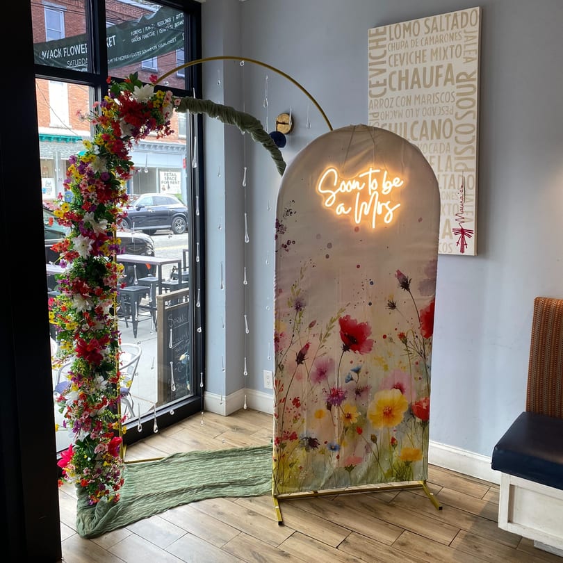 Decorative floral arch and 'Soon to be a Mrs' neon sign in a restaurant with a Peruvian menu.
