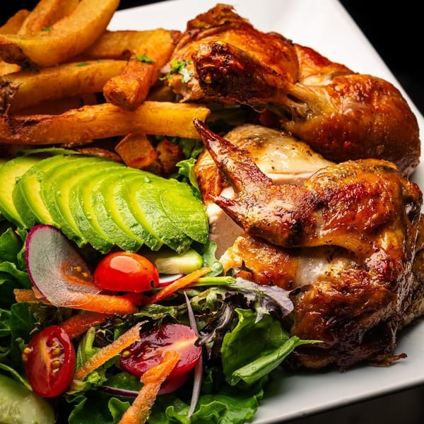 Peruvian rotisserie chicken with crispy fries, sliced avocado, and a fresh garden salad.